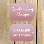 Two pink tags with 'Cookie Dog Designs' text on a wooden background