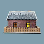 A miniature brick house model with a snow-covered gray roof, two glowing yellow windows, and a beige picket fence around it, shown on a plain blue-gray background.